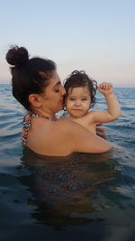 Woman and son in sea against sky