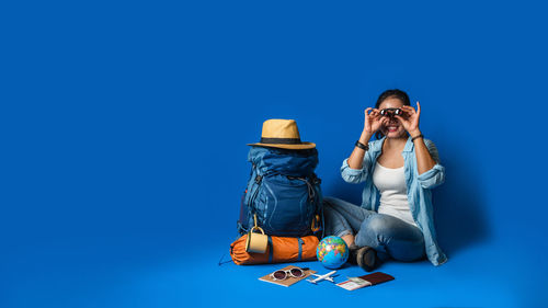 Young woman using phone against blue background