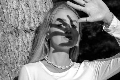 Portrait of young woman with tree trunk