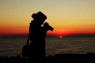 Silhouette woman standing at beach during sunset