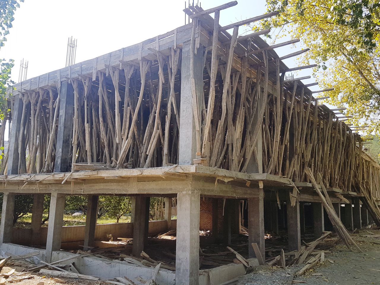 wood - material, thatched roof, day, outdoors, stack, no people, large group of objects, drying, architecture, building exterior, sky