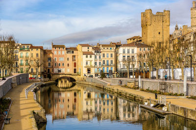 Bridge over river by buildings against sky in city