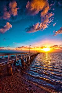 Pier over sea against sky during sunset