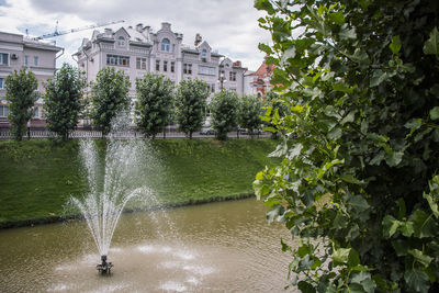 Water fountain against trees and buildings