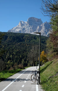 Road amidst trees and mountains against clear sky