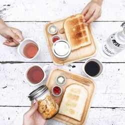 Cropped hands holding food and drink on table