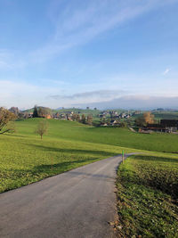 Road amidst field against sky