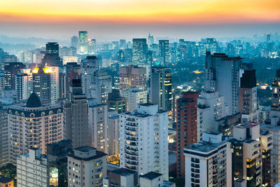 Aerial view of illuminated buildings in city against sky