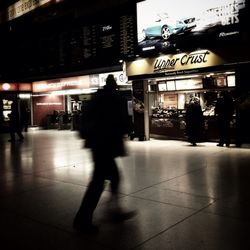 Woman standing on illuminated city street at night