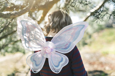 Rear view of boy in fairy wings at yard
