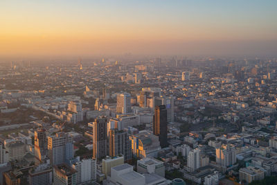 Aerial view of buildings in city against sky during sunset