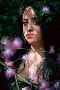 Close-up portrait of beautiful woman by pink flowers