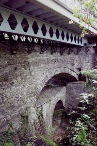 Low angle view of arch bridge by building against sky