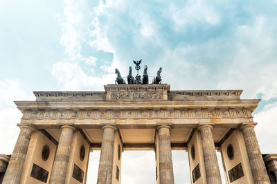 Low angle view of brandenburg gate against cloudy sky