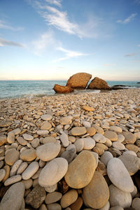 Rocks on shore at beach against sky