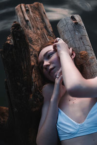 Portrait of young woman lying on tree trunk