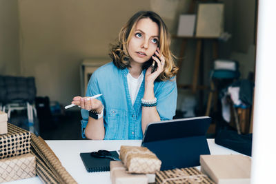 Young woman using phone while sitting on table