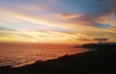 Scenic view of sea against dramatic sky during sunset