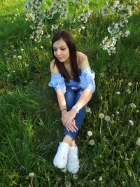 High angle view of young woman sitting on grassy field at park