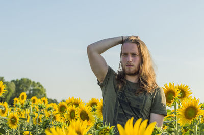 Portrait of young woman with sunflower against clear sky