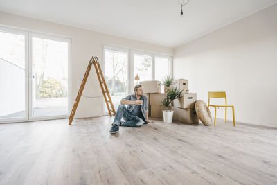 Couple sitting on floor of their new home among moving boxes