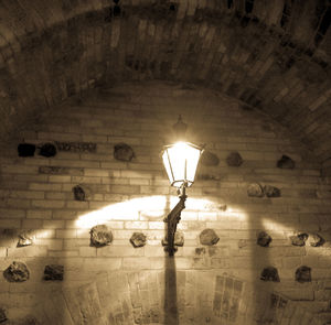 Low angle view of illuminated light bulb hanging from ceiling