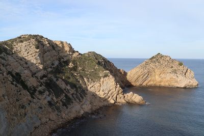 Rock formations by sea against sky