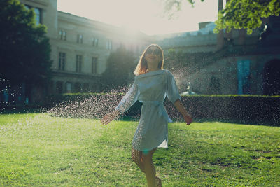 Young woman standing amidst spraying water