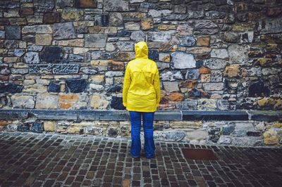 Rear view of man standing against brick wall