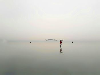 Man standing in sea against clear sky