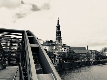 View of buildings by river against sky in city