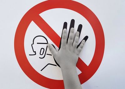 Cropped hand touching information sign against white background