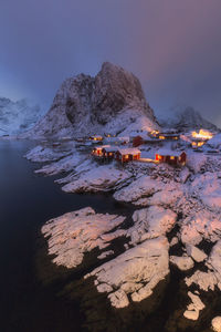 Lake by illuminated mountain against sky at dusk