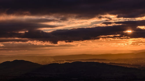 Scenic view of dramatic sky over silhouette landscape