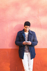 Full length portrait of young man standing against wall