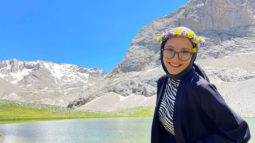 Portrait of young woman standing against mountain