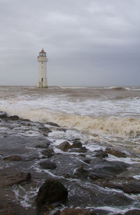 Lighthouse by sea against sky