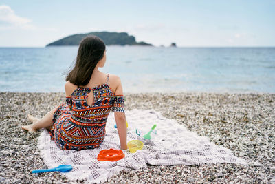 Rear view of woman sitting on beach