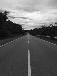 Empty road along trees and against sky