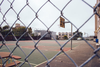 View of cityscape seen through chainlink fence