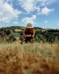 Rear view of woman walking on field against sky