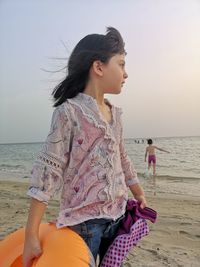 Young woman on beach against sky