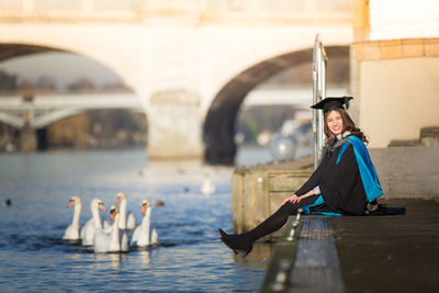 Woman sitting on bridge over water