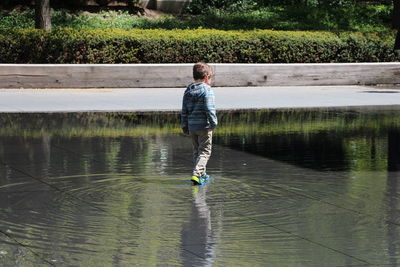 Rear view of boy standing in lake