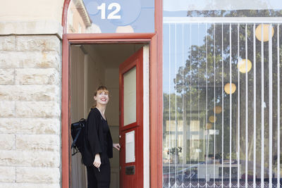 Smiling mid adult businesswoman standing in doorway of office