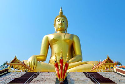 Statue outside temple against building against clear sky