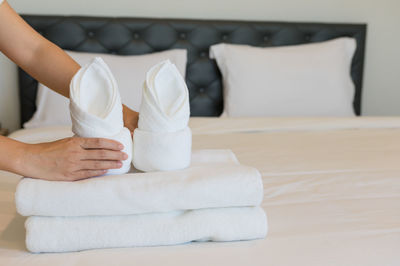 Cropped hands arranging towel on bed in hotel