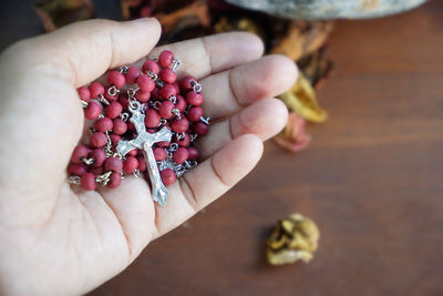 Person holding red rosary in hand. praying rosary concept.