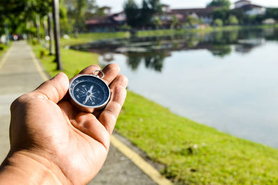 Cropped hand of person holding navigational compass at park