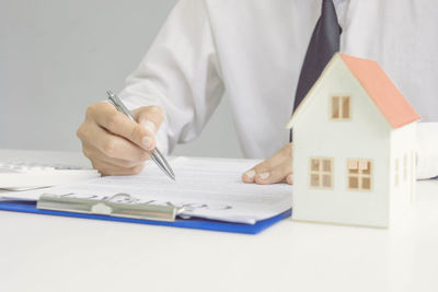 Midsection of real estate agent with contract paper working on table